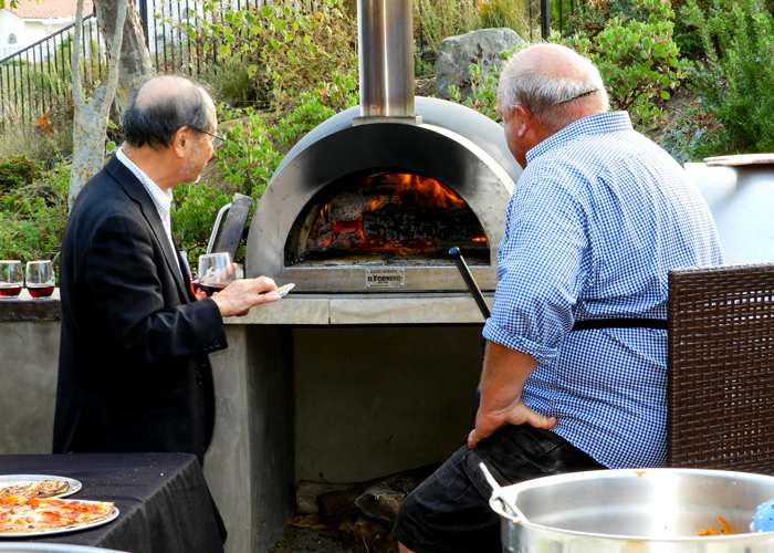 Steve Komine inspects Peder Norby's wood fired pizza oven.